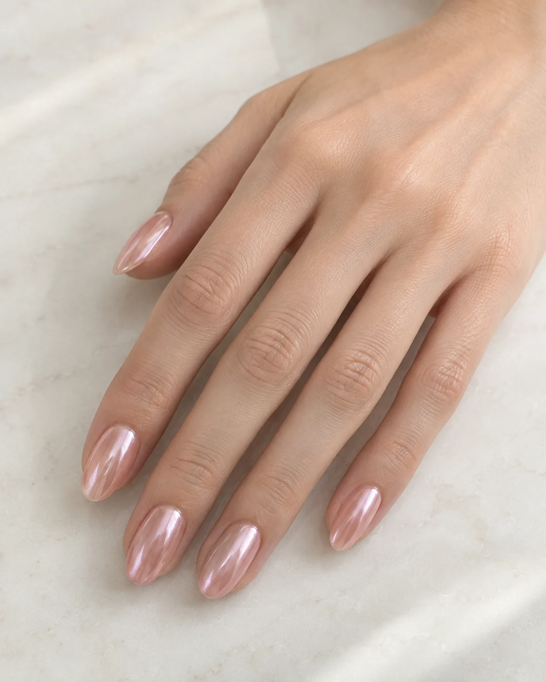 Soft rose-pink chrome polish on oval nails